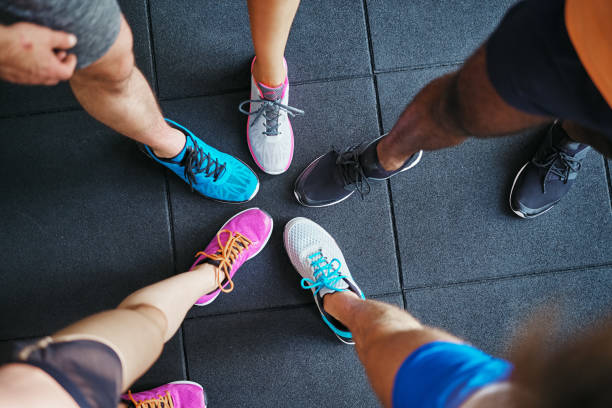 Cercle de pieds en chaussures de sport colorées sur un sol de salle de sport.